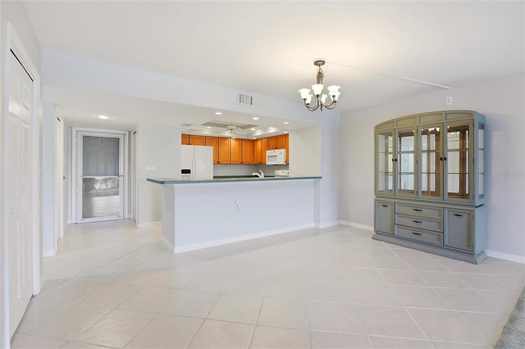 A dining area with tile floors, a hutch, and an open kitchen with wooden cabinets — 601 SHREVE STREET UNIT 25A, PUNTA GORDA, FL