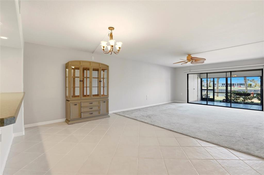 A living and dining area with tile flooring, gray carpet, a hutch, and sliding glass doors — 601 SHREVE STREET UNIT 25A, PUNTA GORDA, FL