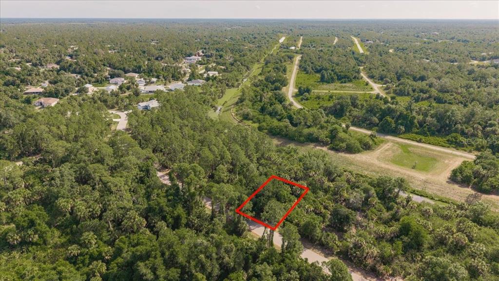 An aerial view shows a rectangular plot of land outlined in red amidst wooded terrain — SERNICE STREET, NORTH PORT, FL