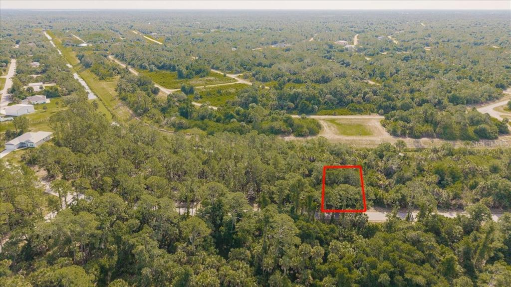 An aerial view shows a wooded residential lot outlined in red along a paved road — SERNICE STREET, NORTH PORT, FL