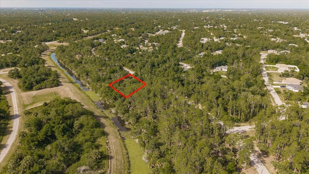 An aerial view shows a vacant, wooded lot outlined in red next to a canal — SERNICE STREET, NORTH PORT, FL