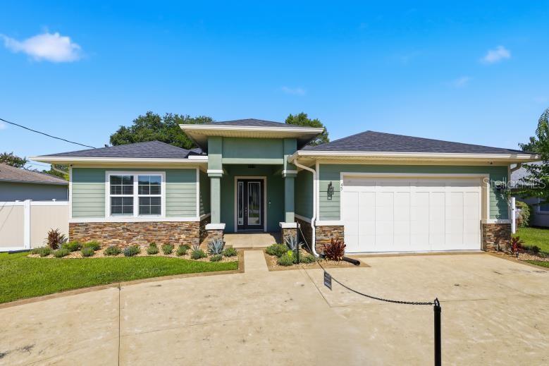 A single-story house with green siding, stone accents, and a two-car garage — 45 LARAMIE DRIVE, PALM COAST, FL