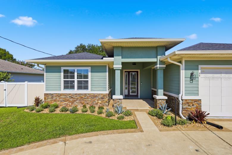 The exterior of a single-story house features green siding, stone veneer, and a concrete driveway — 45 LARAMIE DRIVE, PALM COAST, FL