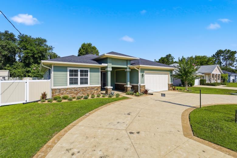 A single-story house with green siding, stone accents, and a large concrete driveway — 45 LARAMIE DRIVE, PALM COAST, FL
