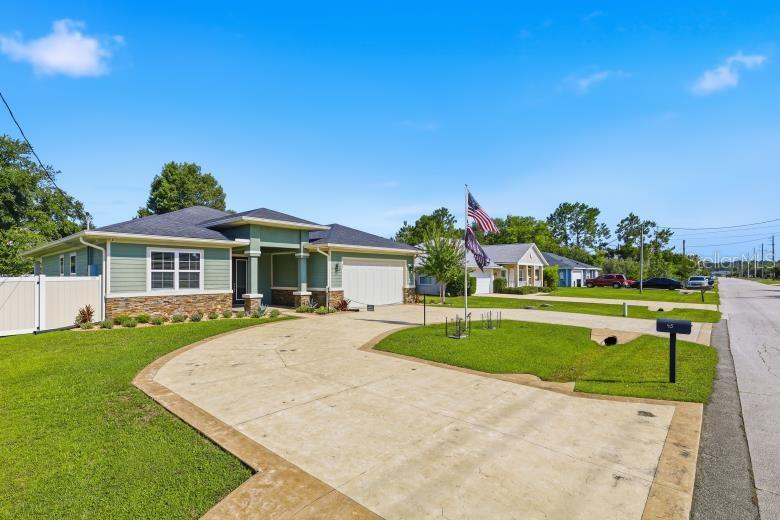 A single-story house with green siding, stone accents, and a large concrete driveway — 45 LARAMIE DRIVE, PALM COAST, FL