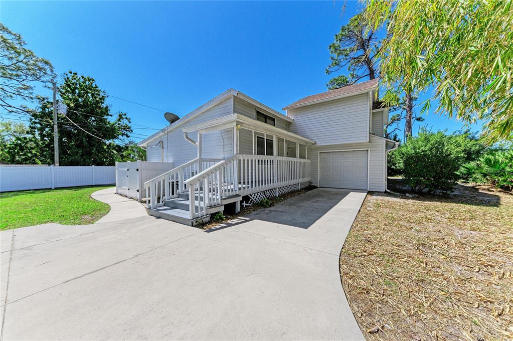 A light-colored house with a wooden deck, stairs, and a single-car garage — 1581 ROYAL ROAD, VENICE, FL