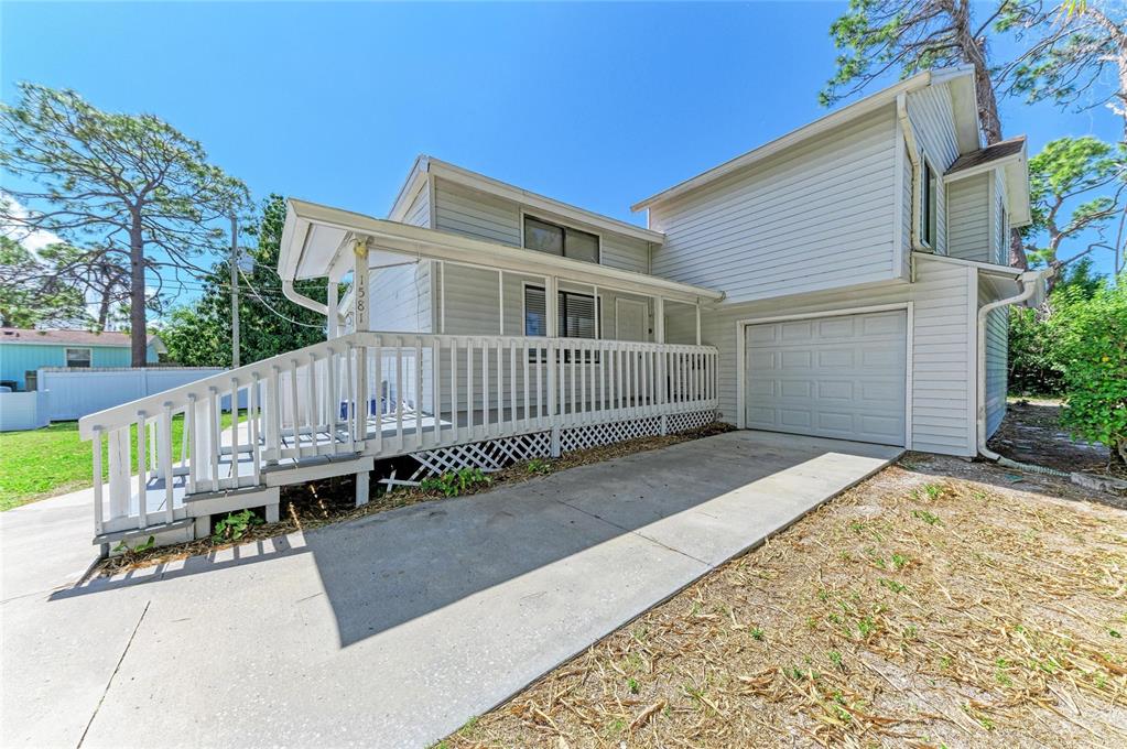 A two-story house with white siding, a garage, and a large front porch with railings — 1581 ROYAL ROAD, VENICE, FL
