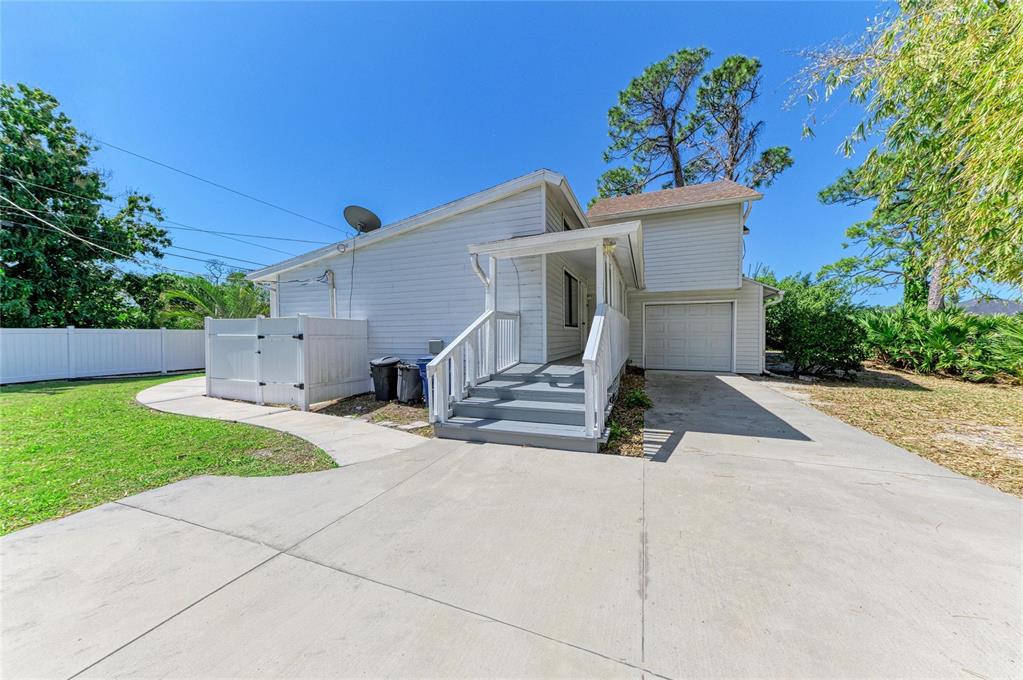 A white house with a concrete driveway, a small front porch, and a garage — 1581 ROYAL ROAD, VENICE, FL