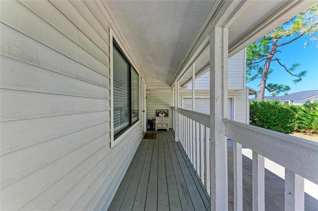 A covered wooden porch with white railings runs along the side of a house — 1581 ROYAL ROAD, VENICE, FL