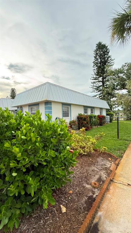 A single-story building with a metal roof sits behind a large green shrub — 4248 TAMARGO DRIVE, NEW PORT RICHEY, FL