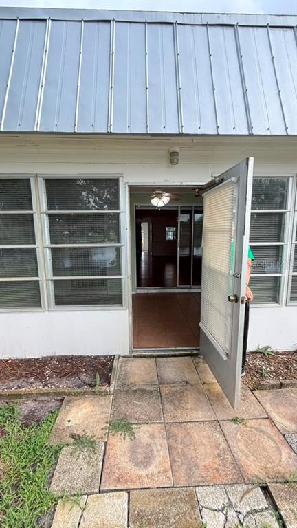A metal-roofed exterior features a tiled patio leading into a room with a ceiling fan — 4248 TAMARGO DRIVE, NEW PORT RICHEY, FL