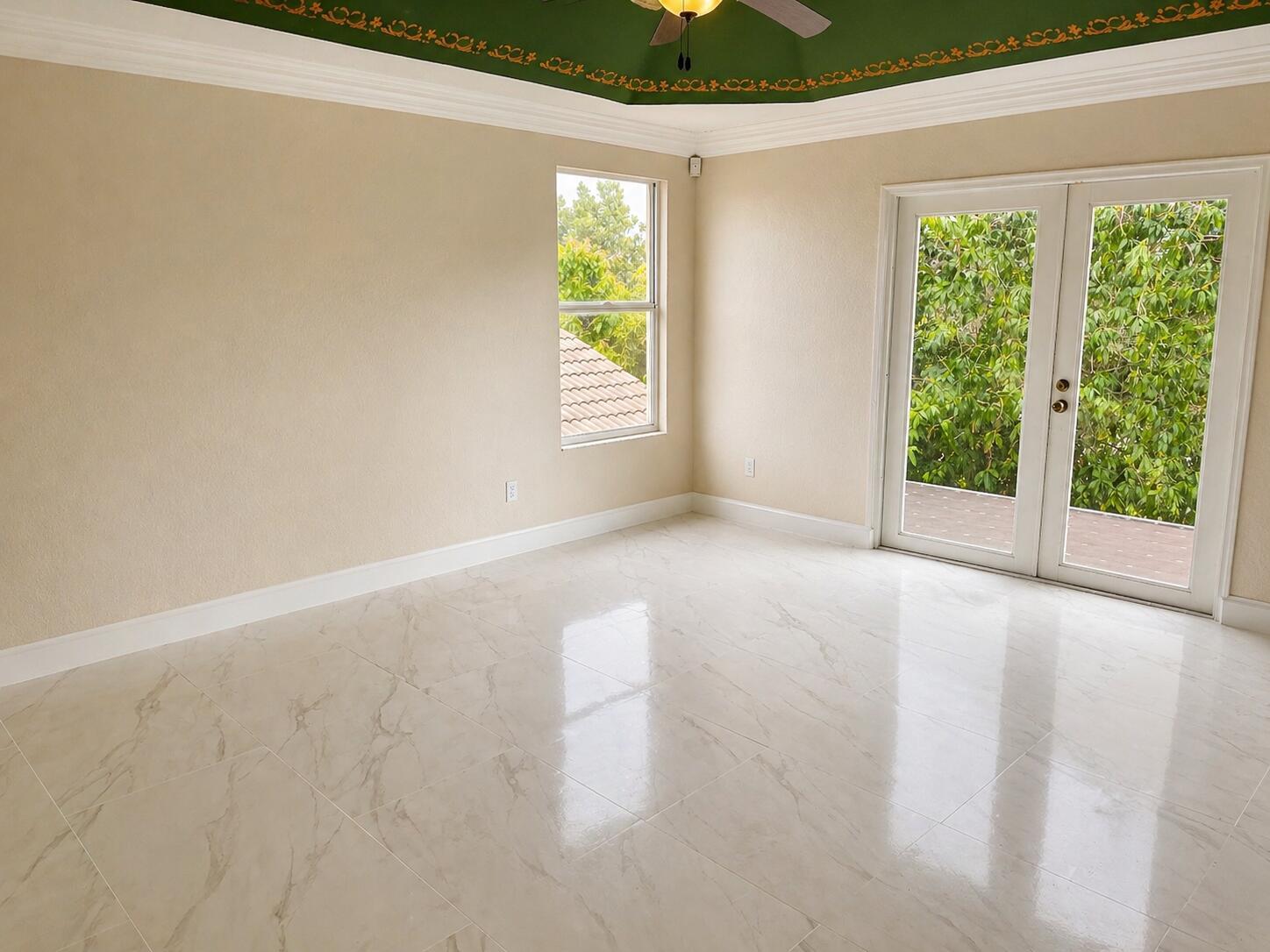 An empty room with beige walls, white marble-look tile flooring, and a green tray ceiling — 5097 Bright Galaxy Lane, FL 33463, FL