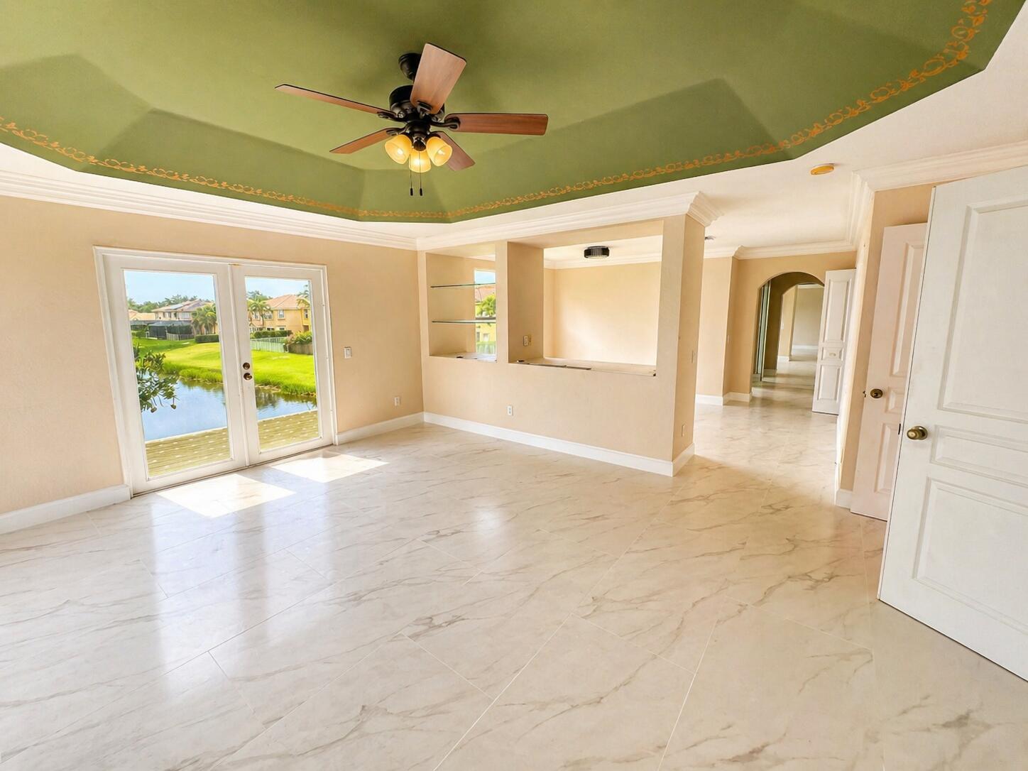 A bright room with marble-look tile floors, a green tray ceiling, and glass doors to a lake — 5097 Bright Galaxy Lane, FL 33463, FL