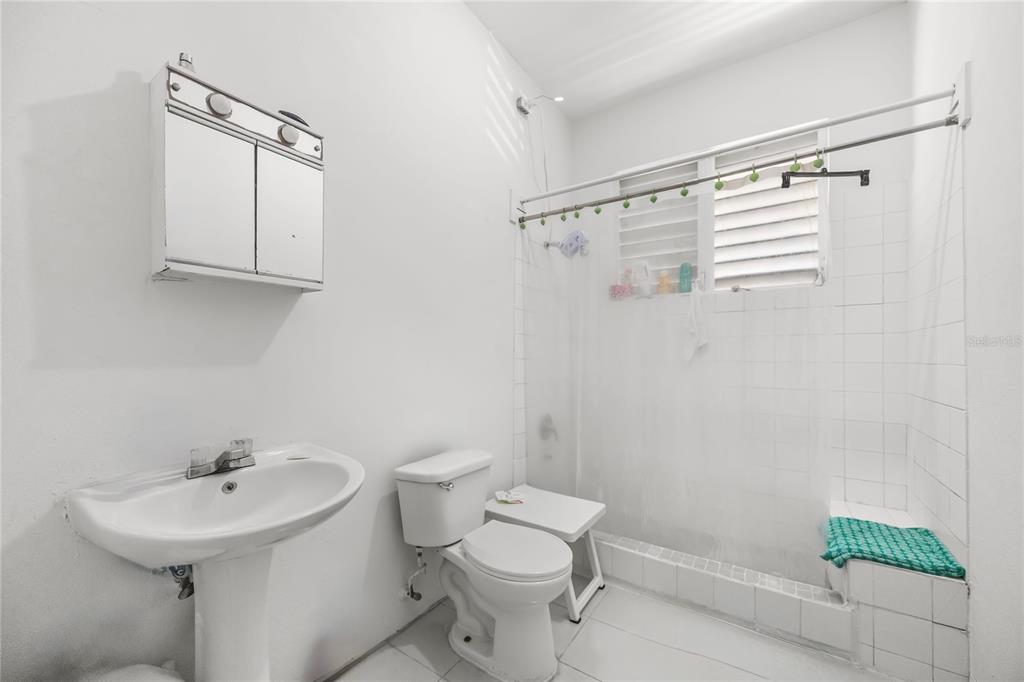 A bathroom features a pedestal sink, a toilet, and a tiled shower area with a curtain — 1410 AMERICO SALAS, SAN JUAN, PR