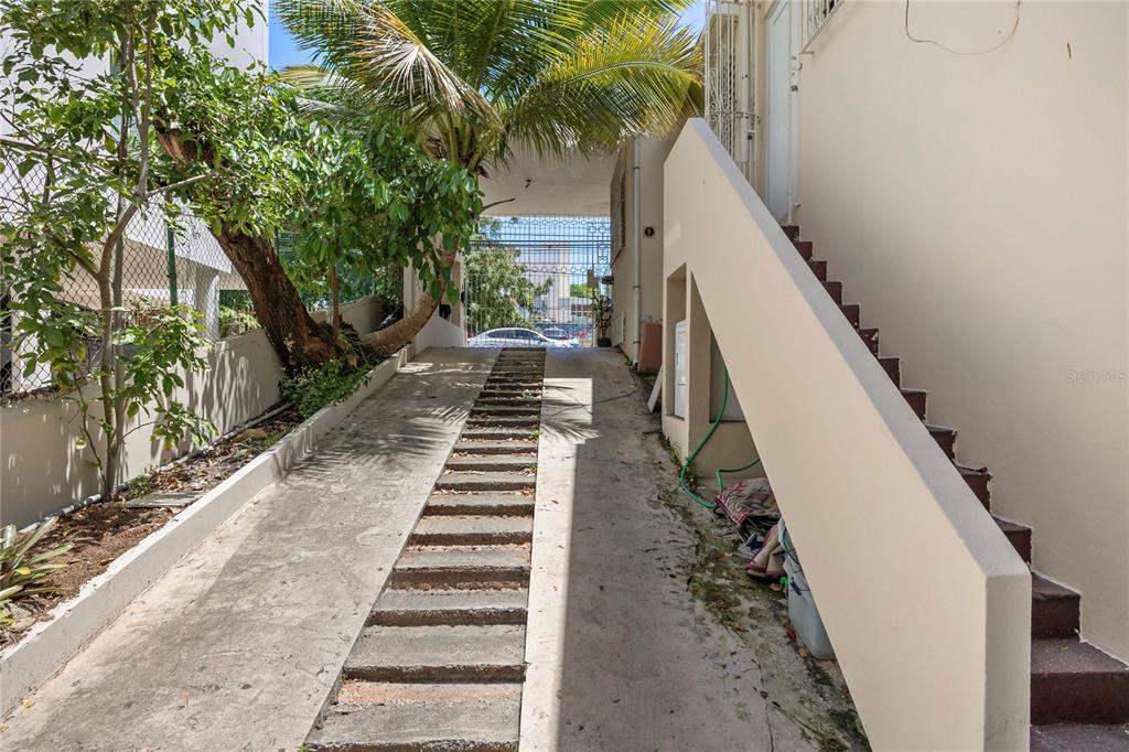 A concrete driveway leads to a gated entrance beside an outdoor staircase and palm tree — 1410 AMERICO SALAS, SAN JUAN, PR