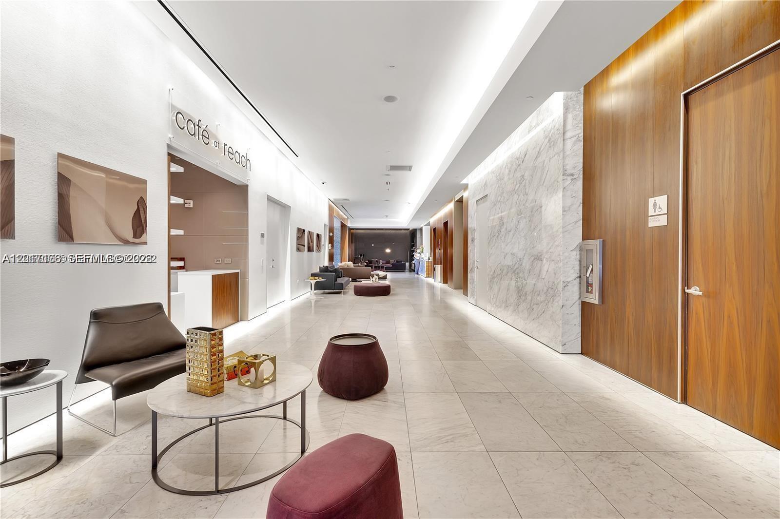 A modern lobby features marble floors, wood-paneled walls, a café, and contemporary seating areas — 68 SE 6th St # 2510, Miami FL 33131, MIAMI, FL