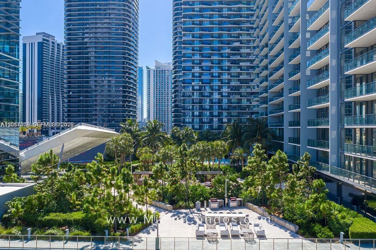 A high-angle view shows a landscaped courtyard with trees and seating between modern skyscrapers — 68 SE 6th St # 2510, Miami FL 33131, MIAMI, FL