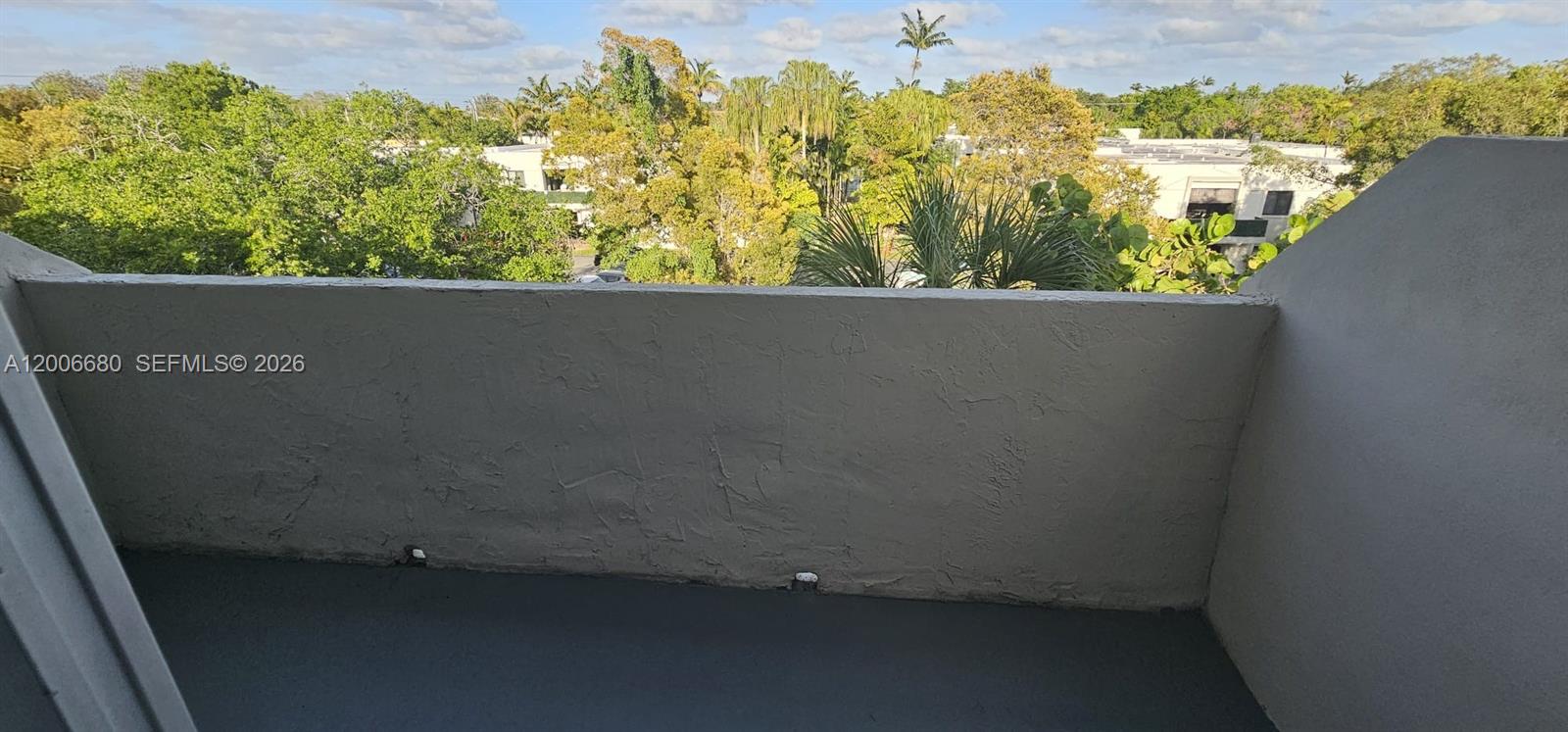 A view from a balcony overlooking trees and nearby buildings under a blue sky — 6884 N Kendall Dr # C404, Pinecrest FL 33156, PINECREST, FL