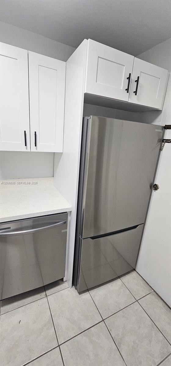 A kitchen features white cabinets, stainless steel appliances, and light-colored tile flooring — 6884 N Kendall Dr # C404, Pinecrest FL 33156, PINECREST, FL