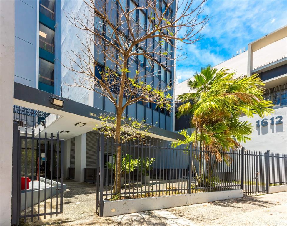 A modern multi-story building exterior features a gated entrance, a bare tree, and palm trees — 1612 PONCE DE LEON AVENUE, SAN JUAN, PR