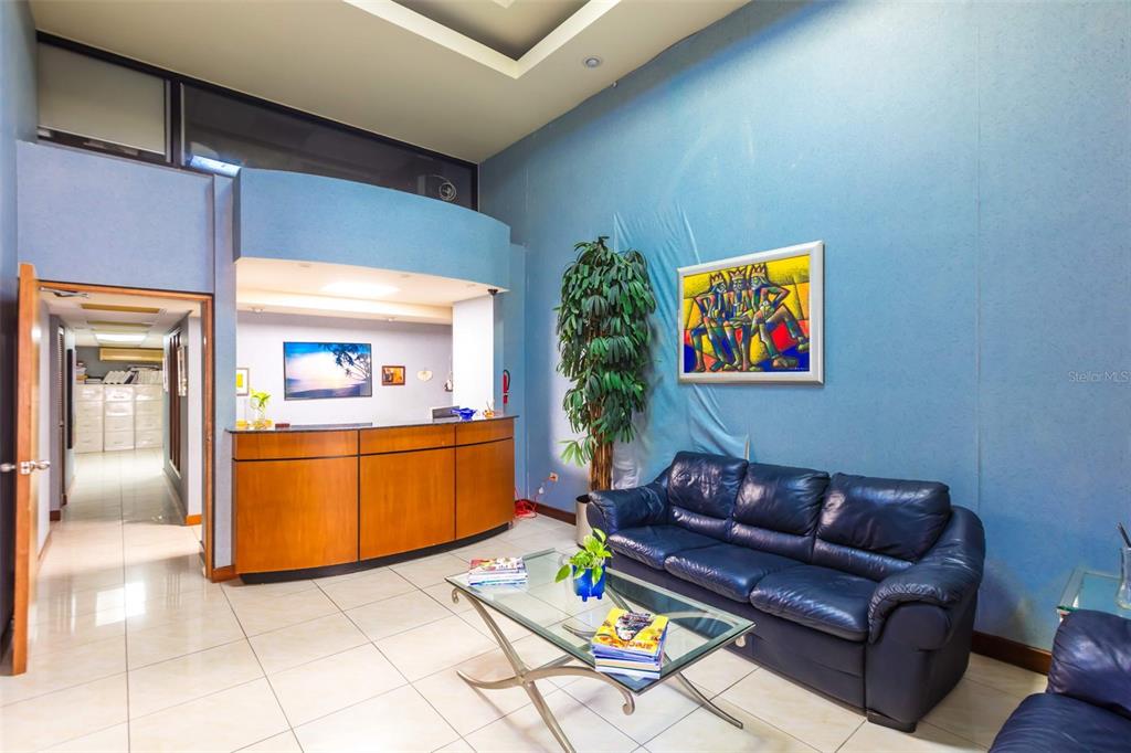 A reception area features a curved wooden desk, blue walls, a leather sofa, and tile flooring — 1612 PONCE DE LEON AVENUE, SAN JUAN, PR