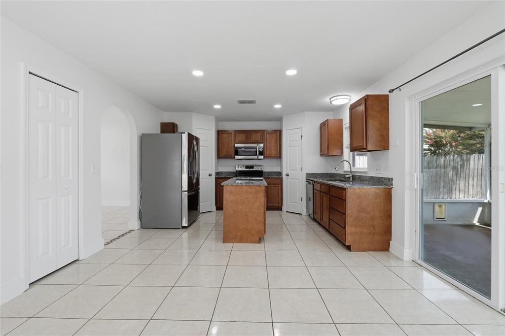 A kitchen with wood cabinets, granite countertops, a center island, and tile flooring — 4140 STONEFIELD DRIVE, ORLANDO, FL