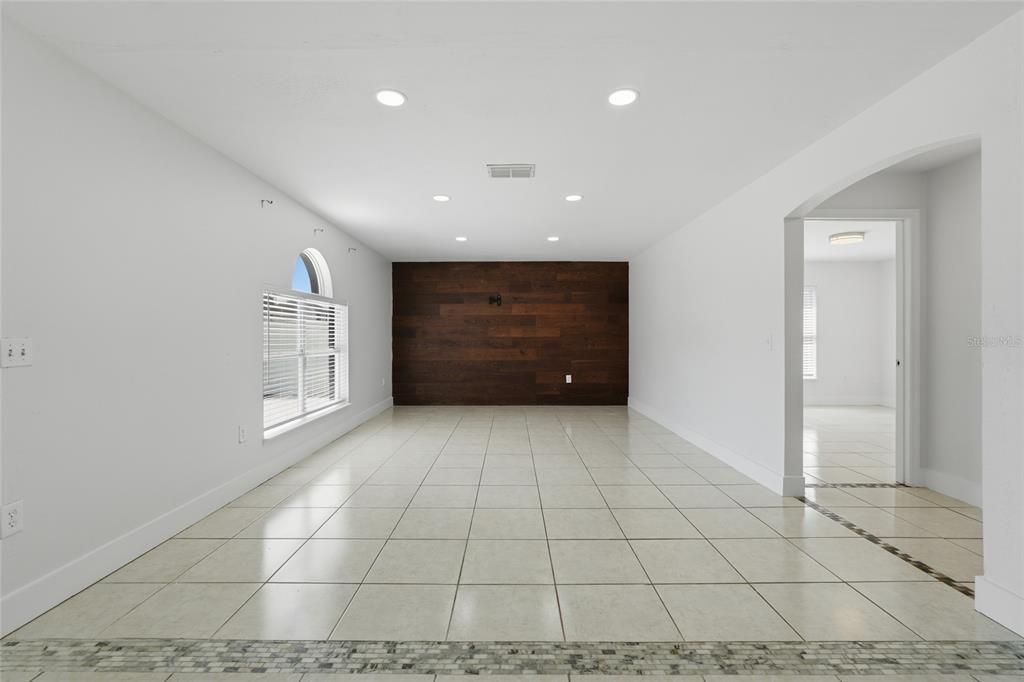 An empty room features white walls, light tile flooring, and a dark wood accent wall — 4140 STONEFIELD DRIVE, ORLANDO, FL