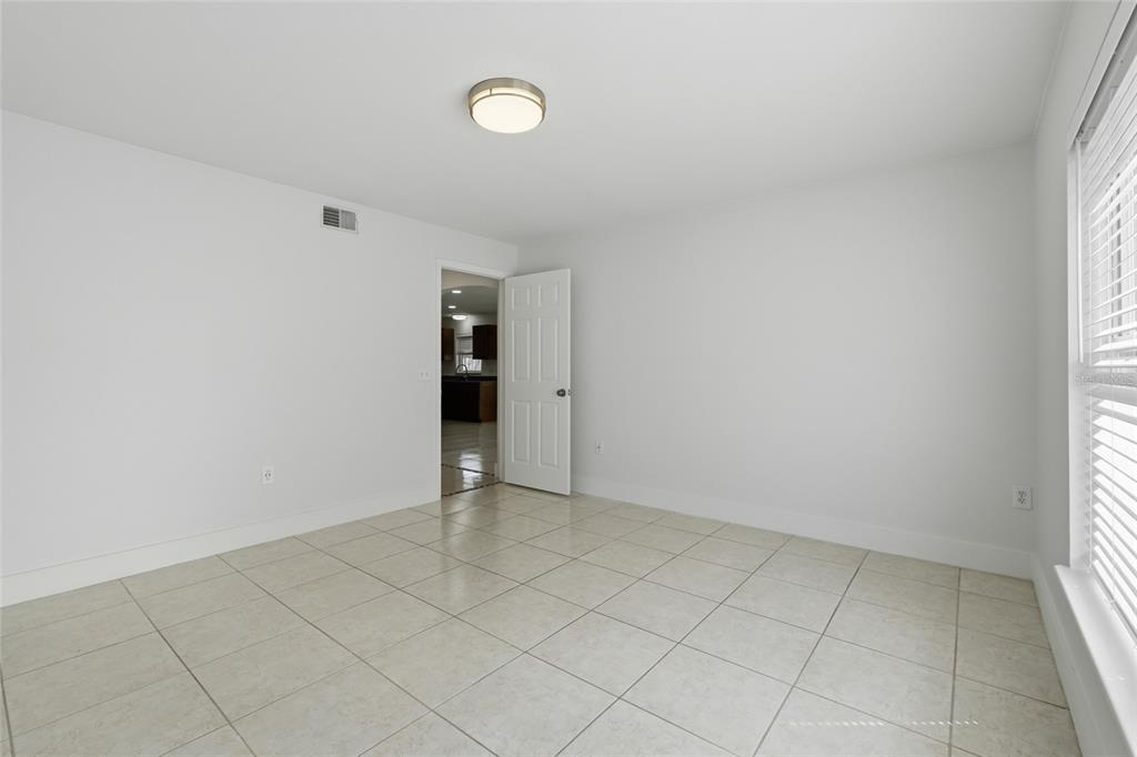 An empty room features white walls, light-colored floor tiles, a ceiling light, and a doorway — 4140 STONEFIELD DRIVE, ORLANDO, FL