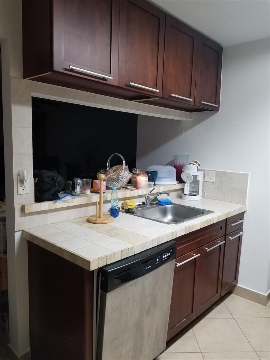 A kitchen features dark wood cabinets, a tiled countertop, a stainless steel sink, and a dishwasher — 3100 N Pine Island Road # 202, Sunrise FL 33351, SUNRISE, FL