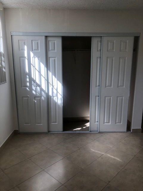 A room with light-colored tile flooring and a white sliding-door closet — 3100 N Pine Island Road # 202, Sunrise FL 33351, SUNRISE, FL
