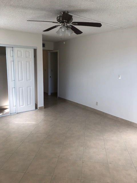 An empty room with light-colored tile flooring, a ceiling fan, and white sliding closet doors — 3100 N Pine Island Road # 202, Sunrise FL 33351, SUNRISE, FL