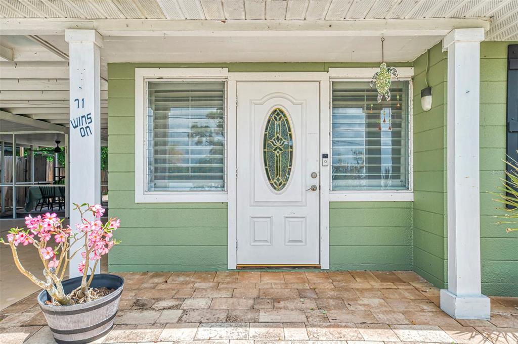 A front porch with a white door, two windows, and a potted plant — 71 WINSON AVENUE, ENGLEWOOD, FL