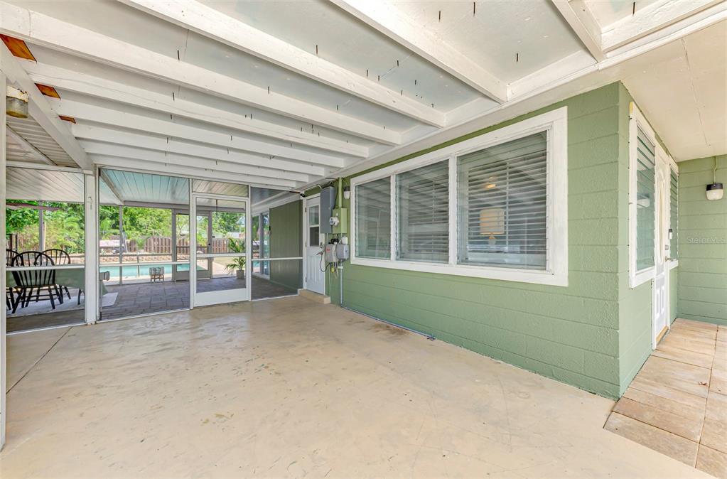 A covered concrete patio features a green exterior wall, large windows, and a screened enclosure — 71 WINSON AVENUE, ENGLEWOOD, FL