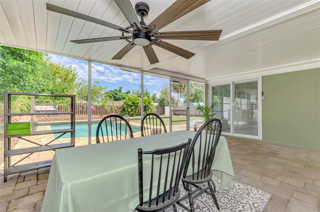 A covered patio features a dining table, ceiling fan, and a view of a swimming pool — 71 WINSON AVENUE, ENGLEWOOD, FL