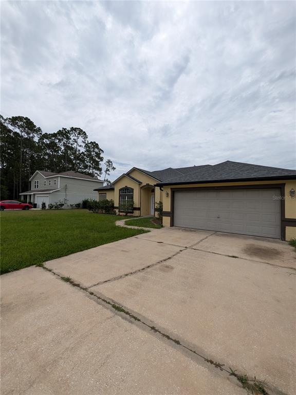 A single-story house with a beige stucco exterior, a gray shingled roof, and a concrete driveway — 43 RAEMOOR DRIVE, PALM COAST, FL