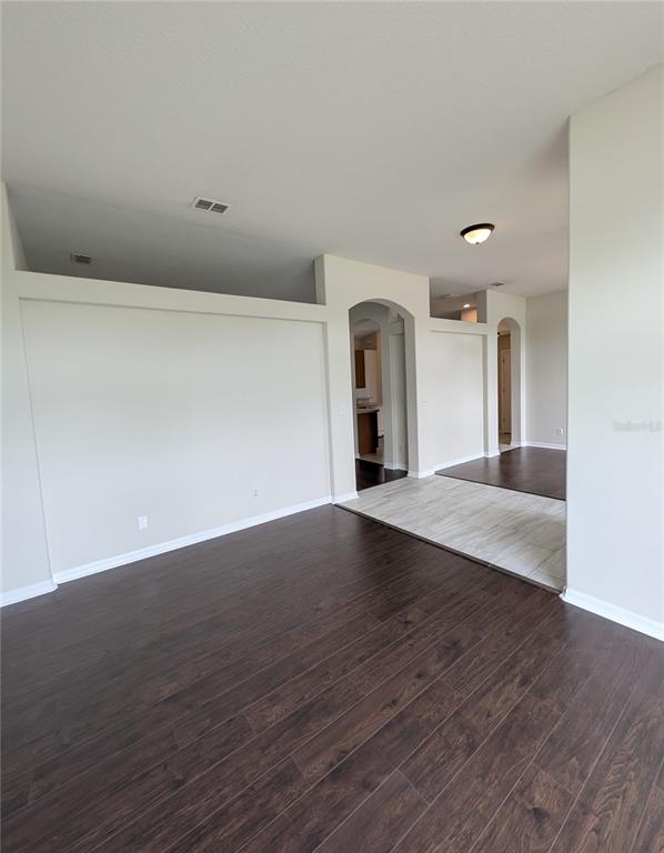 An interior view shows a living area with dark wood flooring and arched wall openings — 43 RAEMOOR DRIVE, PALM COAST, FL