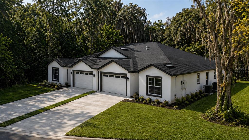 A white single-story house with a black roof and two garages sits on a lawn — 644 and 646 E FRANKLIN STREET, OVIEDO, FL