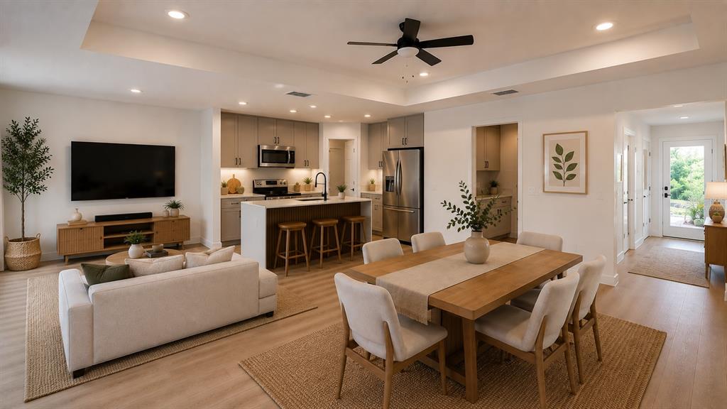 An open-concept living and dining area features a kitchen island, light wood floors, and neutral furniture — 644 and 646 E FRANKLIN STREET, OVIEDO, FL
