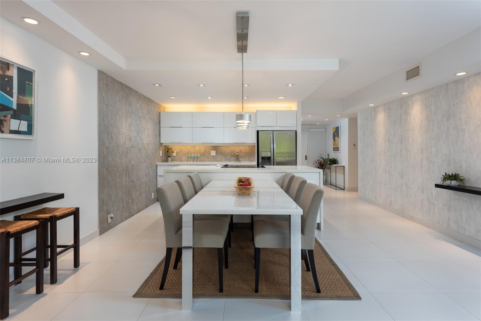 A modern dining area features a white table, six chairs, and a kitchen island — 121 Crandon Blvd # 463, Key Biscayne FL 33149, KEY BISCAYNE, FL