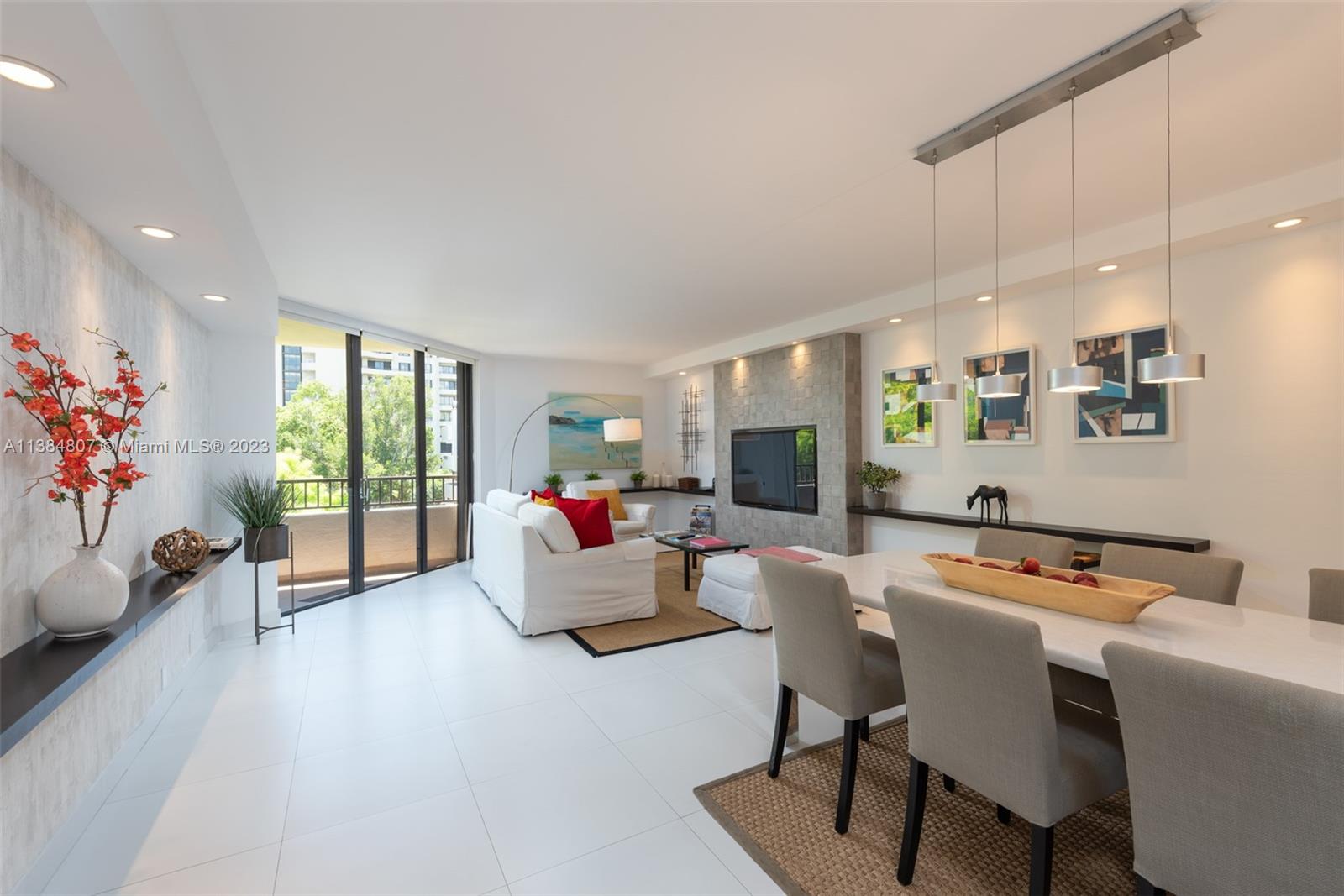 A bright living and dining area features white tile floors, a stone fireplace, and balcony access — 121 Crandon Blvd # 463, Key Biscayne FL 33149, KEY BISCAYNE, FL