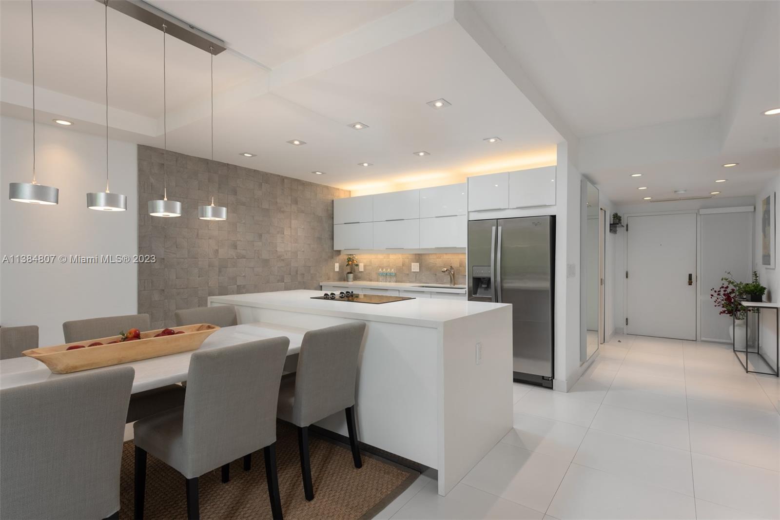 A modern kitchen features white cabinets, a central island, and a dining area with pendant lights — 121 Crandon Blvd # 463, Key Biscayne FL 33149, KEY BISCAYNE, FL