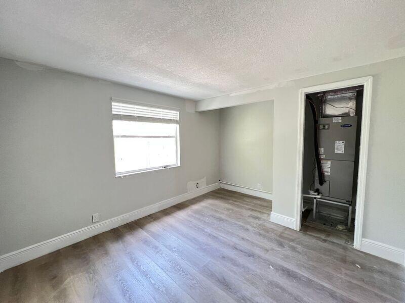 An interior room features light gray walls, wood-look flooring, a window, and an exposed HVAC unit — 6511 Seminole Drive # 2, Atlantis FL 33462, ATLANTIS, FL