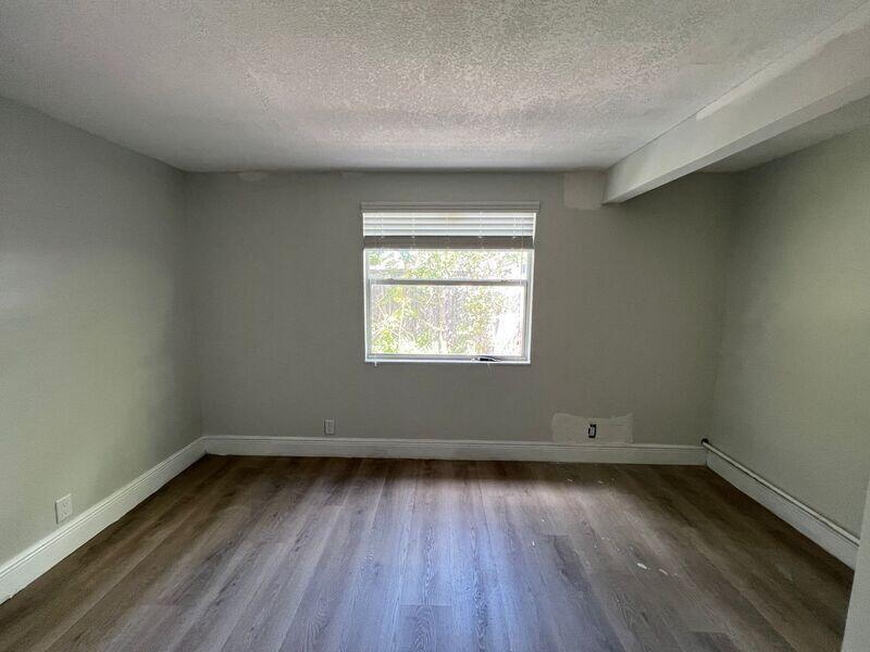 An empty room with light gray walls, wood-look flooring, and a single centered window — 6511 Seminole Drive # 2, Atlantis FL 33462, ATLANTIS, FL