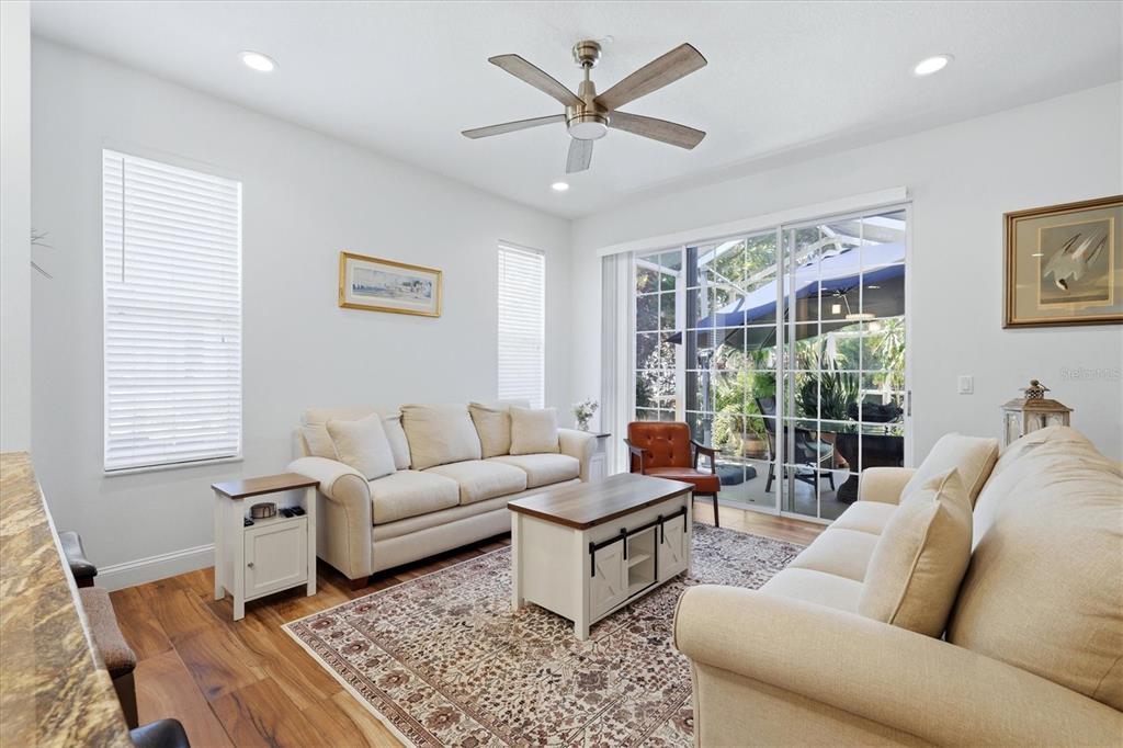 A living room features two beige sofas, a coffee table, and sliding glass doors — 5318 GOLDEN ISLES DRIVE, APOLLO BEACH, FL