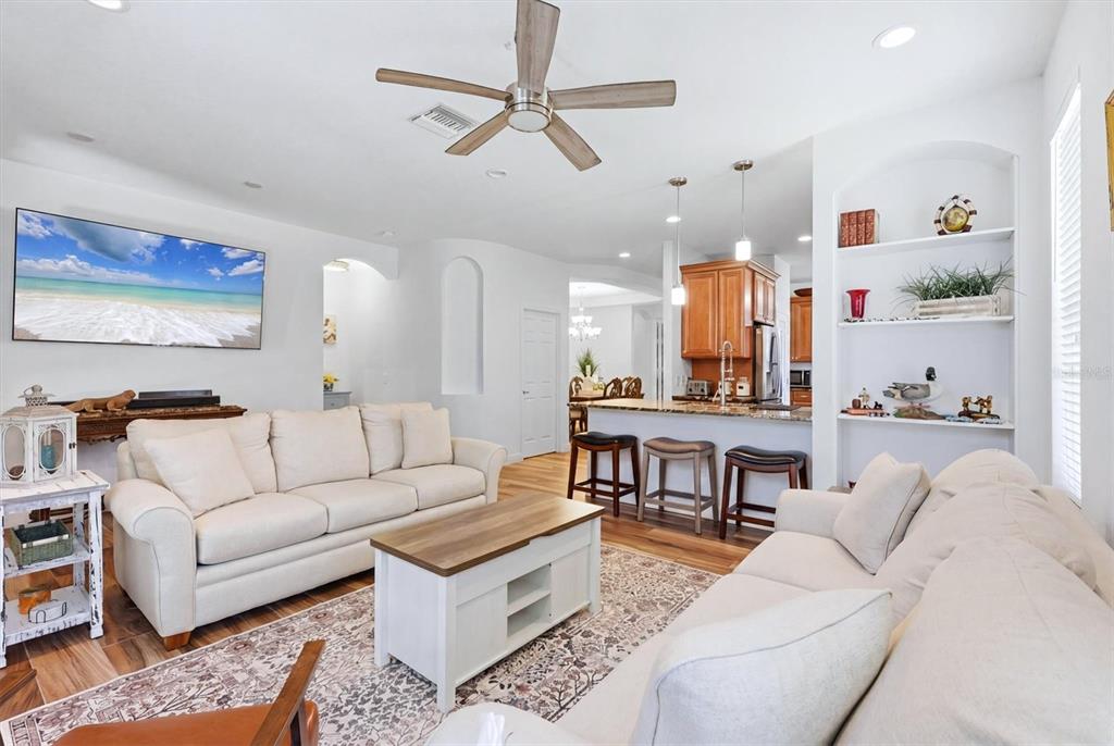 A living room with light-colored sofas, a coffee table, and an open kitchen with barstools — 5318 GOLDEN ISLES DRIVE, APOLLO BEACH, FL
