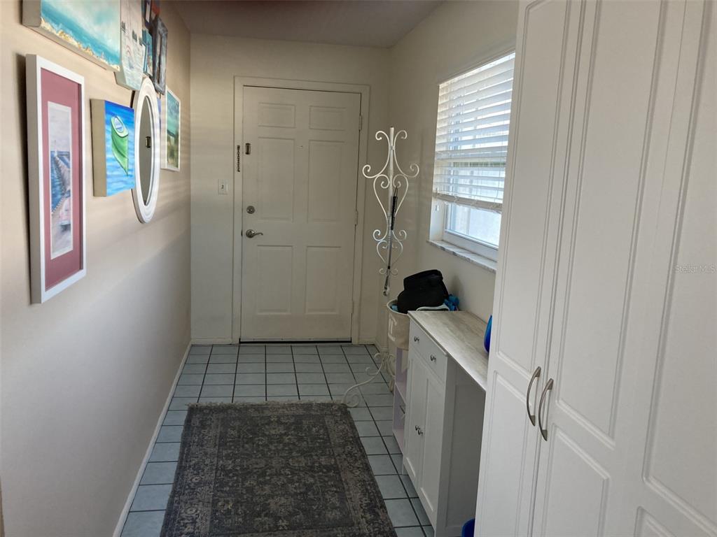 An entryway features tiled flooring, a white front door, a coat rack, and wall art — 304 47TH AVENUE DRIVE W UNIT 307, BRADENTON, FL