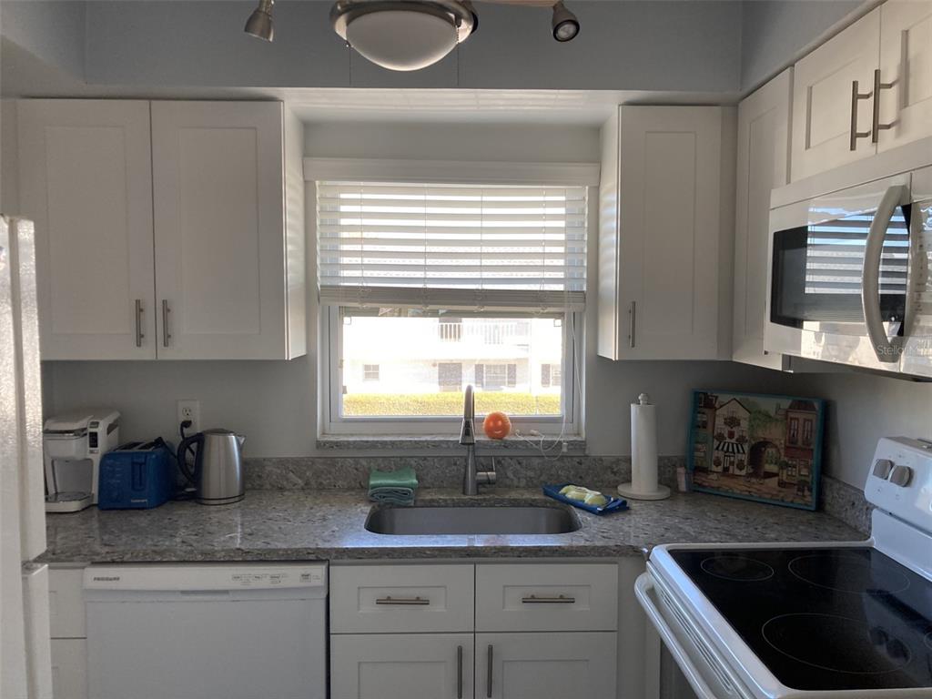A kitchen features white cabinets, granite countertops, a stainless steel sink, and a window — 304 47TH AVENUE DRIVE W UNIT 307, BRADENTON, FL
