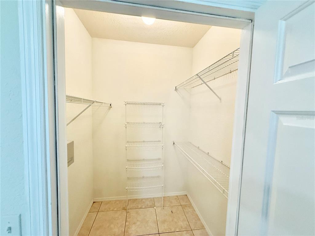 A walk-in closet features white wire shelving, tiled flooring, and a single ceiling light — 2674 ROBERT TRENT JONES DRIVE UNIT 312, ORLANDO, FL