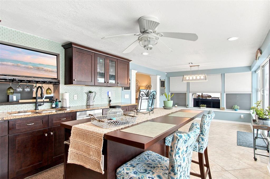 A kitchen features dark wood cabinets, granite countertops, a central island, and a black refrigerator — 415 BRIARWOOD ROAD, VENICE, FL