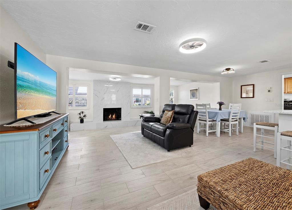 A living room features a fireplace with marble tile, light wood flooring, and a dining area — 726 JUNGLE QUEEN WAY, LONGBOAT KEY, FL
